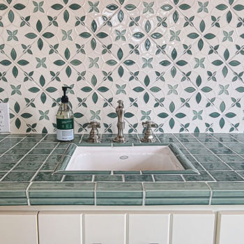 Green and white decorative backsplash with yellow trim. Custom green counter top and sink surround. white cabinet doors. Tile installation by GWH Flooring store in Central Texas.