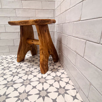 Grey and white star shapes decorative porcelain floor tile in shower with white subway tiles for the wall. Custom wooden stool in the corner. Installation by GWH Flooring in Wimberley.
