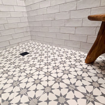 Grey and white star shapes decorative porcelain floor tile in shower with white subway tiles for the wall. Installation by GWH Flooring in Wimberley.