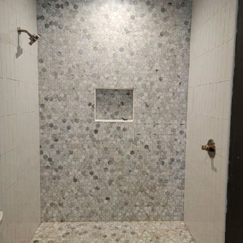 Grey and white small hexagon shaped mosaic tiles for shower back wall and floor. Two other walls are vertical white subway tiles. Installation by GWH Flooring in Wimberley.