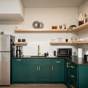 White and gold mosiac tile. Black granite countertops and pine floating shelves with gold faucet and cabinet hardware. Dark green cabinets. Tile installed by GWH Flooring in San Marcos, Texas