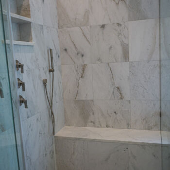 quartzite tile shower large squares for wall, and small squares for floor. Hidden drain, bench, and niche. Installation by GHW Flooring in Wimberley
