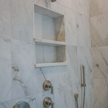 Gold and white quartzite tile shower large squares for wall, and small squares for floor. Hidden drain, bench, and niche. Installation by GHW Flooring