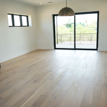 White oak floor installed in a media room with blue cabinets and slatted backing for TV. Installation in Driftwood by GWH Flooring company.