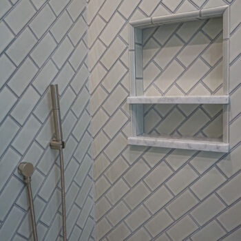 White subway tiles installed on the diagonal in shower. Glass door, shower niche. Installation by GWH Flooring in Central Texas Hill Country