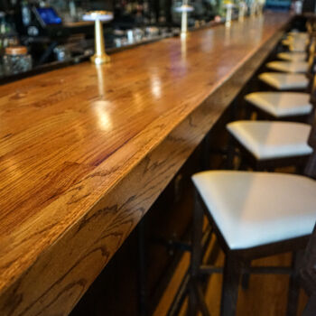 Custom wood bar installed by GWH Flooring Contractors in Buda, Texas. Liquor bottles in the background.