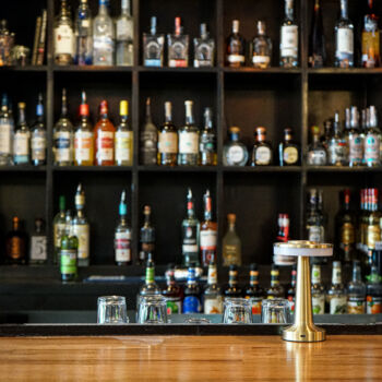 Custom wood bar installed by GWH Flooring Contractors in Buda, Texas. Liquor bottles in the background.