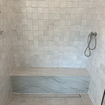 Grey Zia tile in shower with hidden drain and quartz seat. Installation by GWH Flooring store