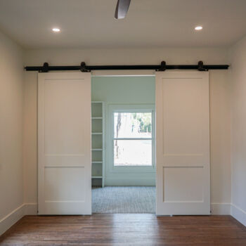 Luxury Vinyl Tile (LVT) in badroom and beber carpet in the closet, separated by white barn doors. Flooring installed by GWH flooring company