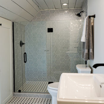 Grey hexagon shower tile with black and white floor tile installed by GWH Flooring company