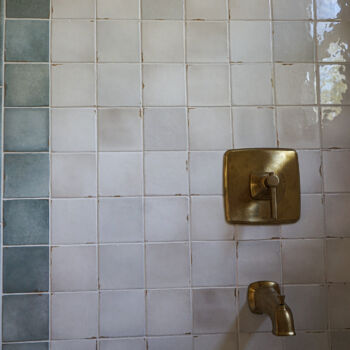 White square tile with blue square tile border in a shower with beautiful brass hardware installed by GWH Flooring company