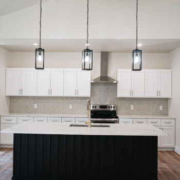 New kitchen with gold and white silestone countertops with brass faucet with undermounted stainless kitchen sink, grey herringbone subway tile, and wood floors installed by GWH Flooring company.