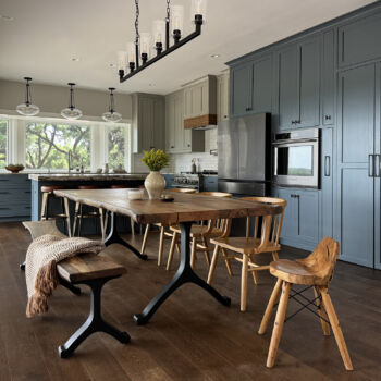 custom wood dining table on wood floors in open kitchen with custom blue cabinets.