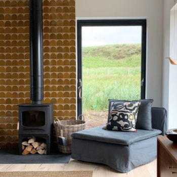 Boho style living area with woodfire stove and ochre colored cement tiles for chimney breast. Tiles by Otto